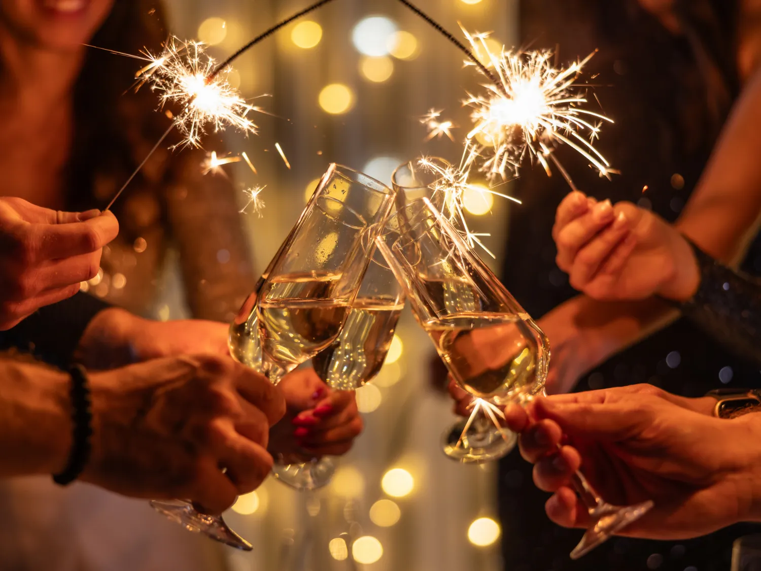 Champagne glasses raised with sparklers on New Year's Eve