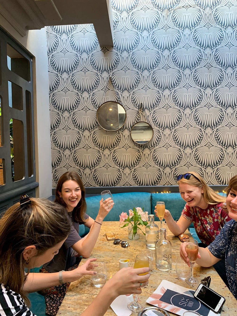 Friends sharing drinks around a table at SIX