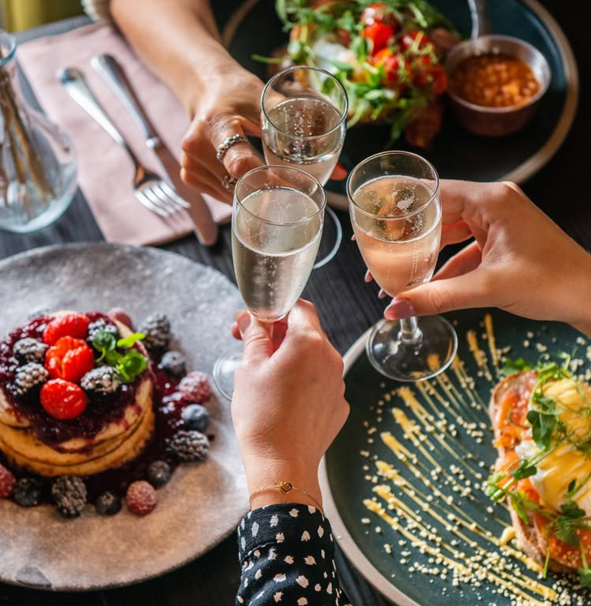 Friends raising glasses of fizz over a festive brunch table