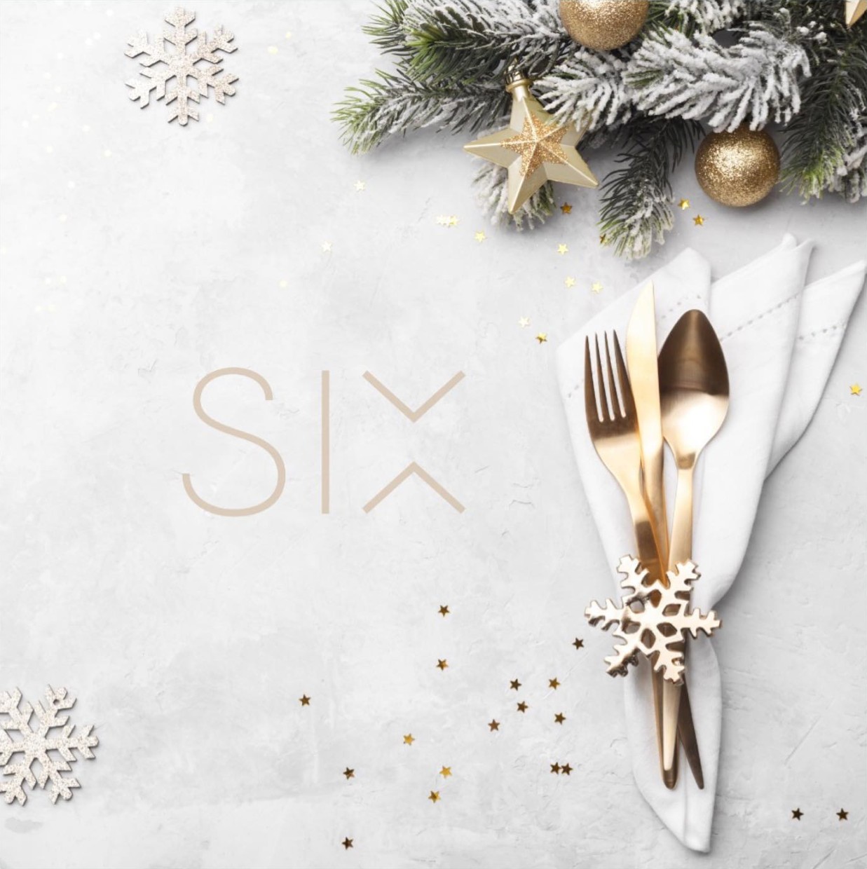 Gold cutlery wrapped in a white napkin beside the SIX logo and festive decorations